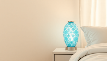 A soft blue and white Turkish mosaic glass bedside lamp glowing on a clean, minimalist nightstand