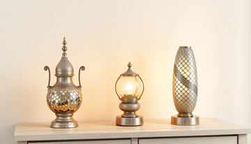 Three silver-toned Turkish mosaic glass lamps of different shapes glowing together on a light wooden console table
