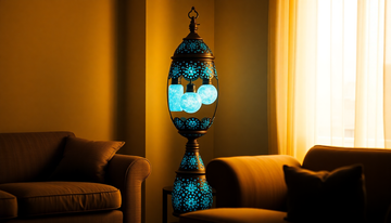 A tall egg-shaped Turkish mosaic glass floor lamp with three glowing globes in deep blue tones standing beside a sofa