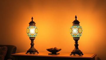 Two coordinating Turkish mosaic table lamps flanking a console table, glowing warm amber and blue against a neutral wall