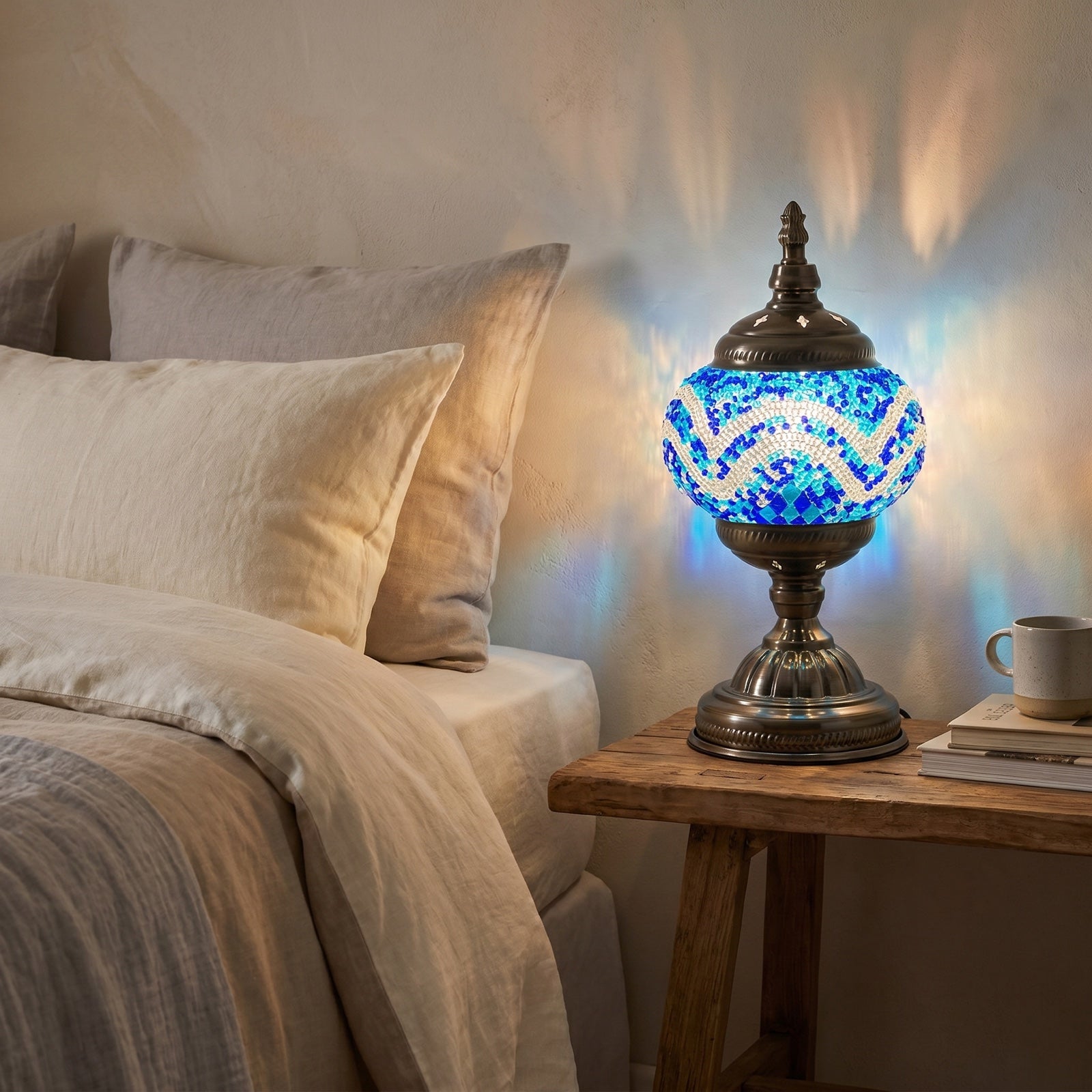 Blue mosaic glass table lamp glowing on a bedroom nightstand