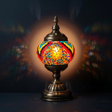 Floral Spectacle mosaic glass table lamp — glowing against a deep charcoal background