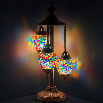 Floral Spectacle mosaic glass table lamp — glowing against a deep charcoal background