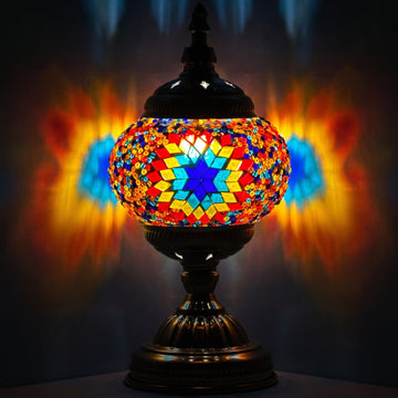 Kaleidoscope Dreams mosaic glass table lamp — glowing against a deep charcoal background
