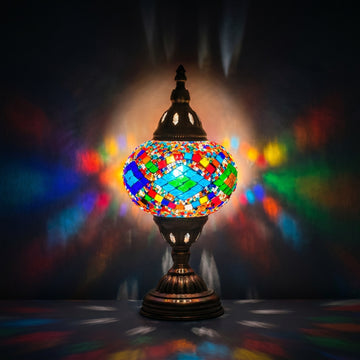 Kaleidoscopic Diamond Road mosaic glass table lamp — glowing against a deep charcoal background