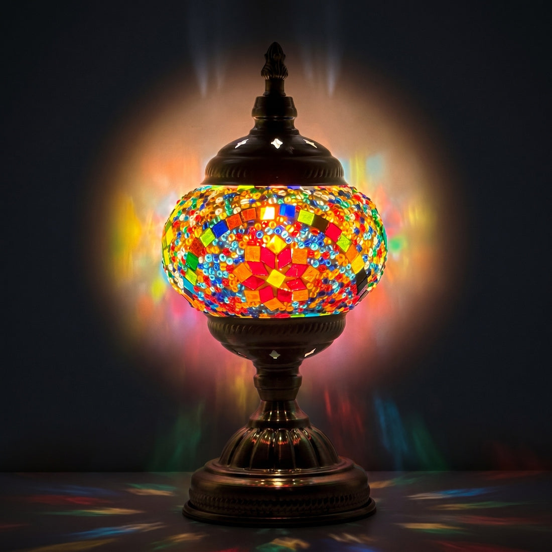 Multicolored Blossom mosaic glass table lamp — glowing against a deep charcoal background