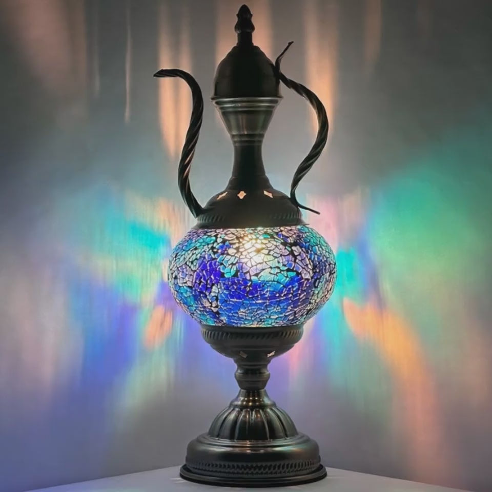 Close-up ambiance video of the mosaic glass ewer lamp glowing and shimmering in a darkened room