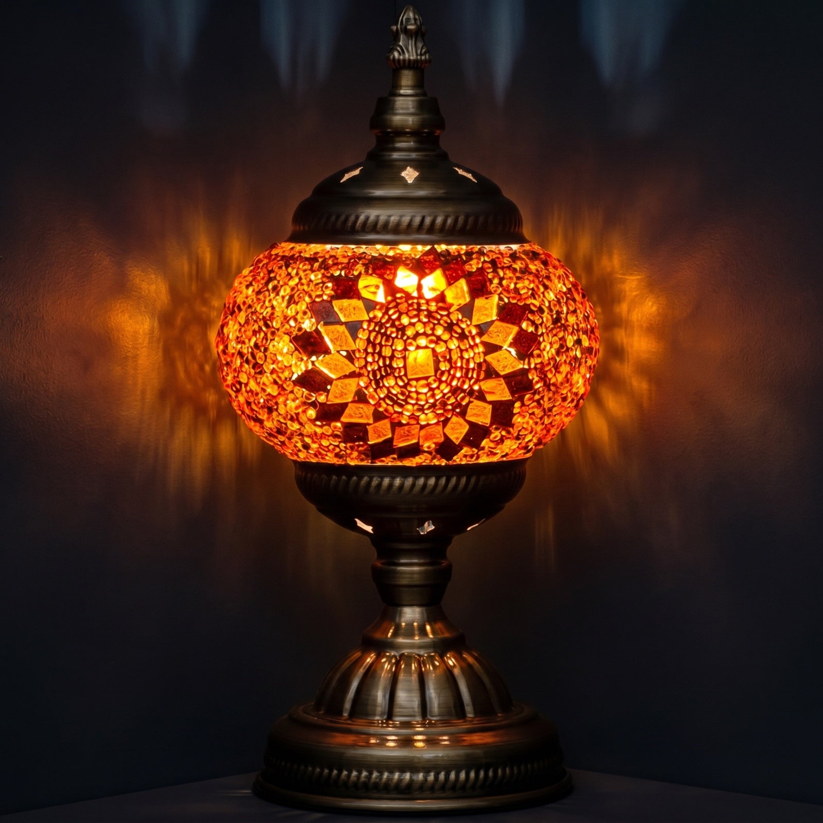 orange mosaic glass table lamp glowing warmly against a dark moody background