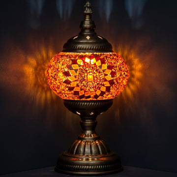 orange mosaic glass table lamp glowing warmly against a dark moody background