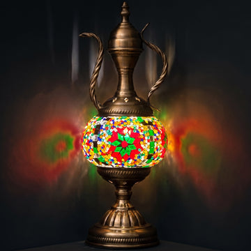 green vintage mosaic glass table lamp with an ornate pitcher-shaped body glowing softly against a dark background