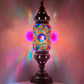 a colorful lamp is lit up on a table